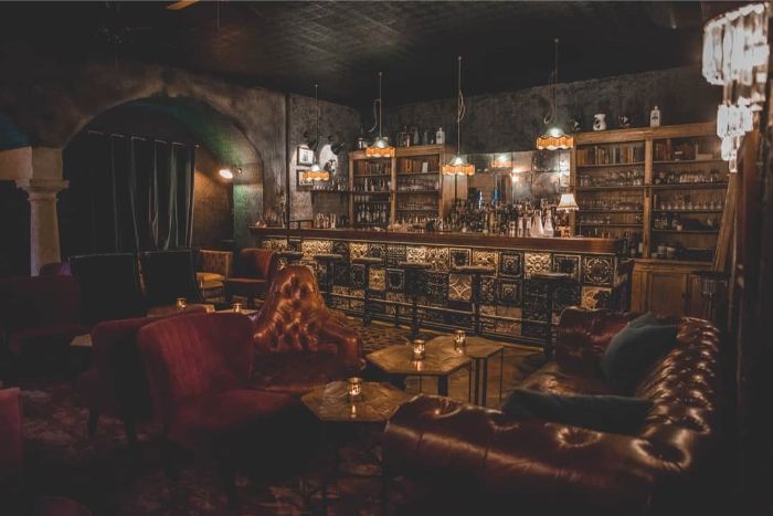 Michalska-cocktail-room-bar-kozene-kreslo-kozena-sedacka-zaclony-zavesy-barovy-pult-vintage-luster-sviecky-stol-vankuse-drinky-koktejly-flase-alkohol